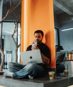 Someone working on a laptop by Loop's orange column, a Loop cup beside them