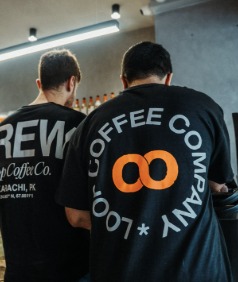 Two of the Loop team from behind, in 'Loop Coffee Company' and 'Brew' shirts