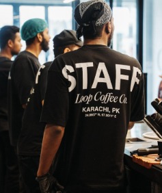 The Loop staff behind the bar, 'STAFF Loop Coffee Co. Karachi, PK' on a shirt